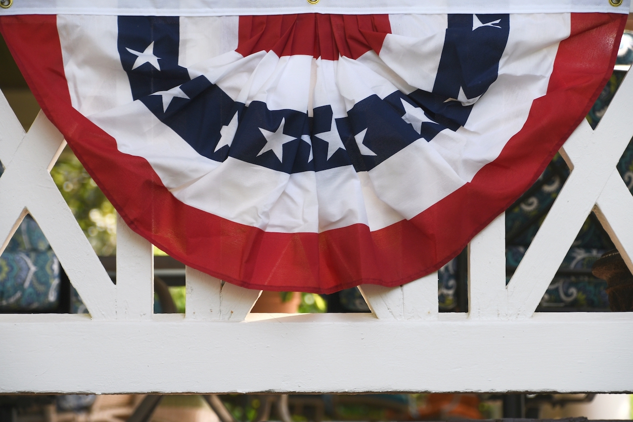 american flag bunting hanging on railing of a front gate