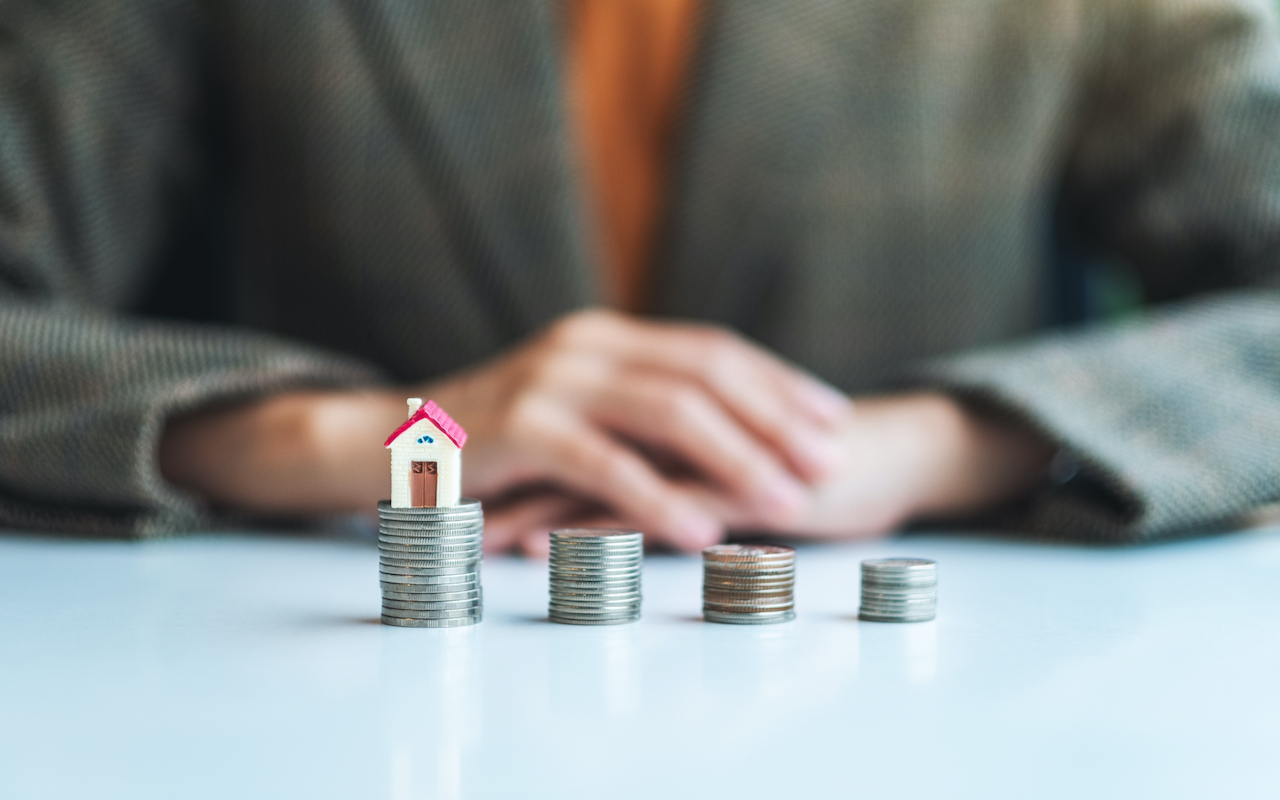 Closeup image of a businessman and a house model on the top of coins stack for saving money concept