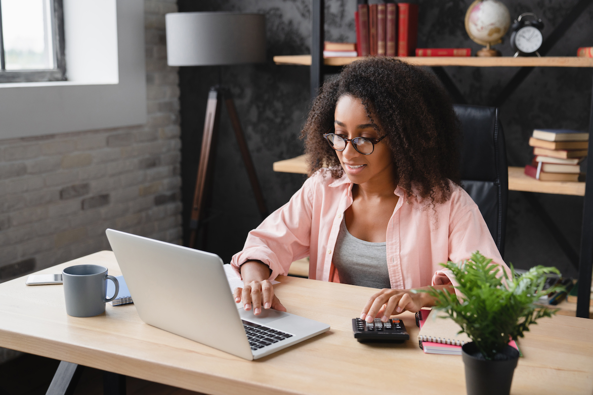 Freelancer counting funds domestic bills on calculator using laptop for e-banking, debt, and loan