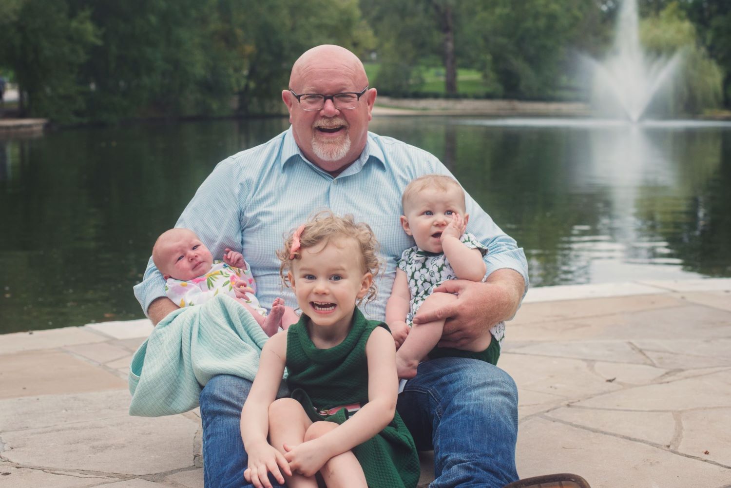 photo of a man beside a pond with his young kids